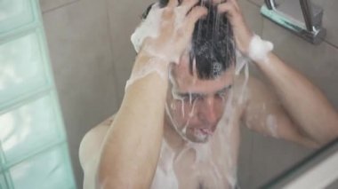 Adam saçlarını duşta yıkıyor.