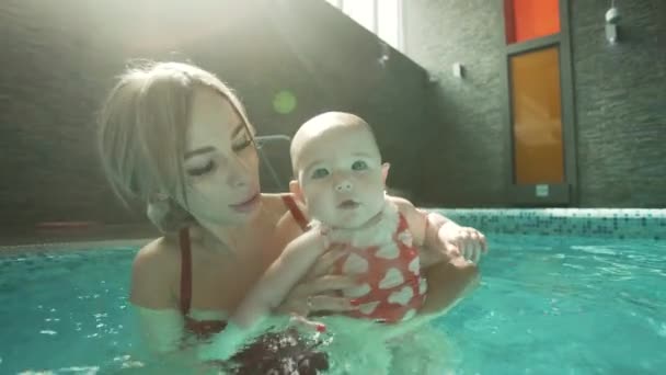 Mujer con su bebé en la piscina — Vídeo de stock