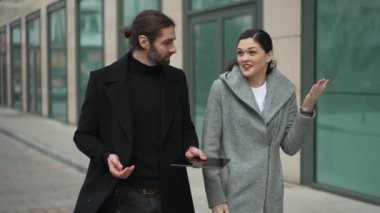 İş adamları sokakta yürür ve konuşur.