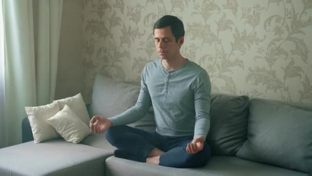 Egy férfi a kanapén meditál. — Stock videók