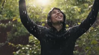 Yağmur altındaki mutlu adam el kaldırıyor.