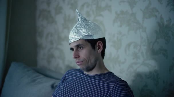 Dziwny mężczyzna w kapeluszu z folii aluminiowej ogląda telewizję — Wideo stockowe