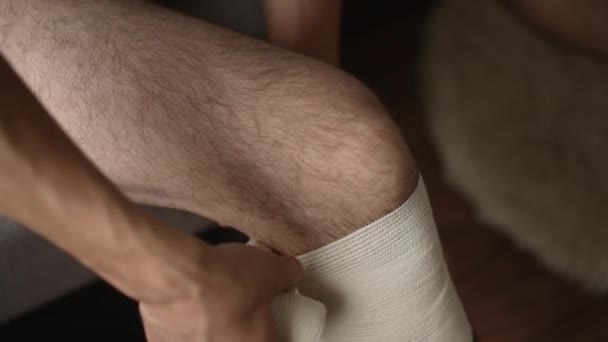 L'uomo si sta fasciando il ginocchio con una benda elastica — Video Stock