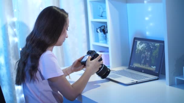 Mujer mirando a través de fotos de la cámara delante de la computadora portátil — Vídeos de Stock