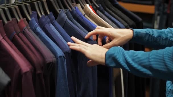 Homem escolhendo camisa na loja de roupas — Vídeo de Stock