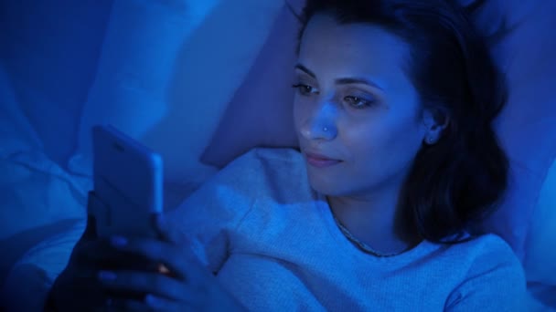 Жінка використовує смартфон у ліжку — стокове відео