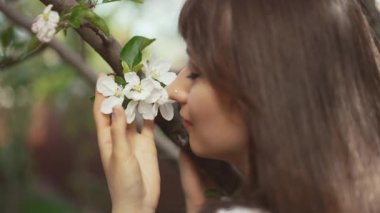 Ağaçtaki çiçekleri koklayan kadın