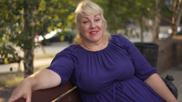 Boldog kövér nő ül egy padon — Stock videók