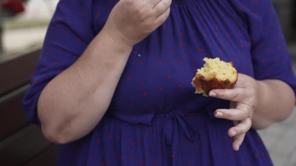 Dikke vrouw die broodjes eet op straat — Stockvideo