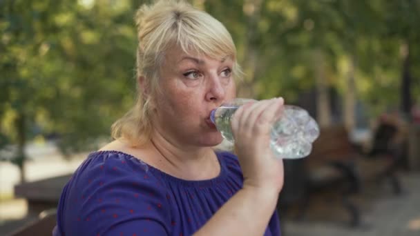 Χοντρή γυναίκα πίνει νερό στο δρόμο. — Αρχείο Βίντεο