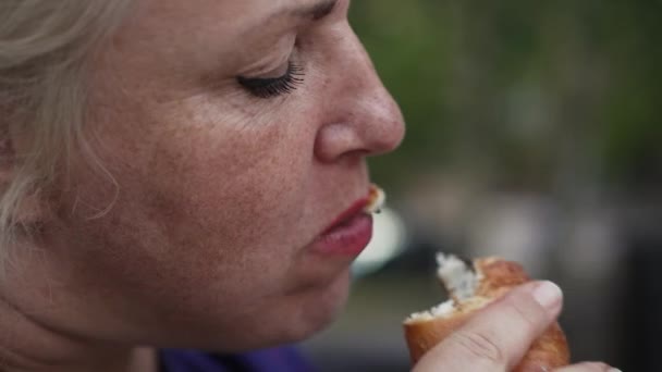 Obese vrouw eet broodjes op straat. Ongezond voedselconcept — Stockvideo