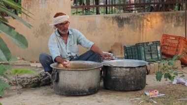 İşçi, büyük olasılıkla sokak yemeklerinden veya etkinliklerden sonra kullanılmış tabak ve çatal bıçak temizler.