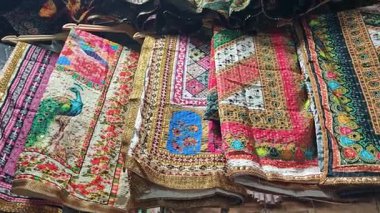 Geleneksel bir Hint pazarının hareketli dar sokaklarında satıcılar tarafından satılığa çıkarılan parlak renkli sariler.