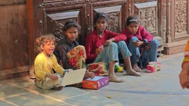 Bir kaç çocuk Hindu tapınağının süslü kapılarının yanında yerde oturuyor.