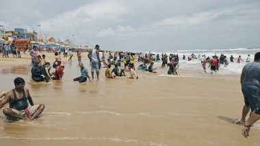 Binlerce renkli elbiseli ziyaretçinin olduğu popüler bir Hint plajının geniş bir görüntüsü..