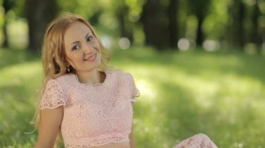 Çimenlerin üzerinde oturan gülümseyen romantik kadın