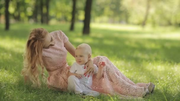 Матері грати зі своєю дитиною в парк на траві — стокове відео