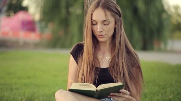 Frau liest Buch am Baum im Park — Stockvideo