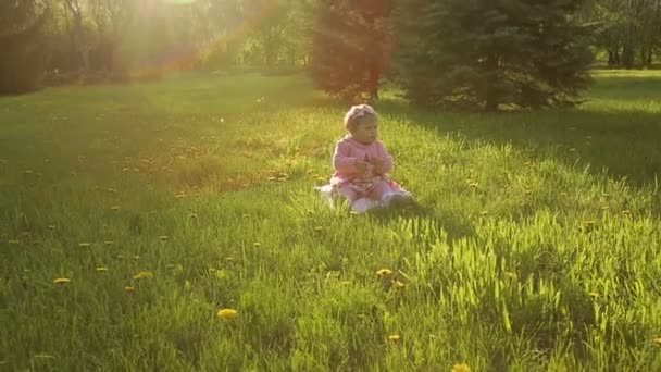 Дитина сидить на траві в парку — стокове відео