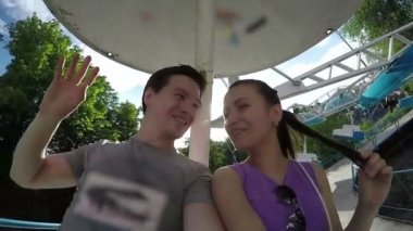 Genç aile bir atlıkarınca üstünde el sallayarak