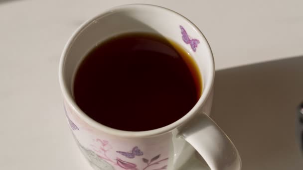 Verser du sucre sur la tasse de thé 