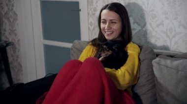 Onun kollarında küçük bir köpekle TV izlerken kadın