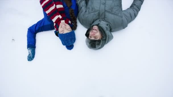 Pareja joven tumbada en la nieve — Vídeo de stock