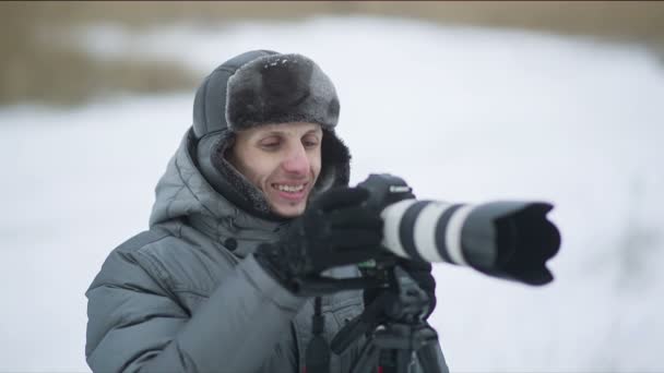 Улыбающийся фотограф на открытом воздухе зимой — стоковое видео