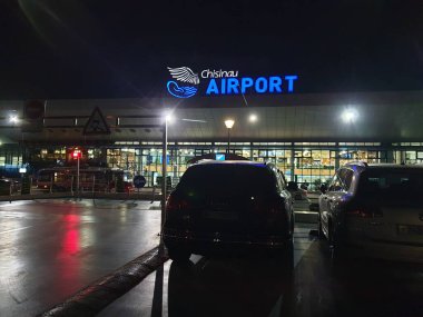 Çilingir, MOLDOVA. 23 Ağustos 2019. Arabalar Kishinev Chisinau uluslararası havaalanı terminali girişinin önüne park edilmiş ve gece güzel bir neon ışığı var. Terminal binası yenilendi.