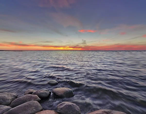 Západ slunce s kameny na jezeře — Stock fotografie