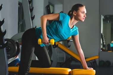 Dumbbells ile egzersizleri yapıyor spor salonunda Fitness sportif genç seksi kadın