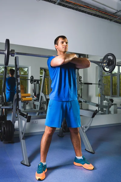 Deporte, culturismo, estilo de vida y el concepto de la gente - joven con barra haciendo sentadillas en el gimnasio — Foto de Stock