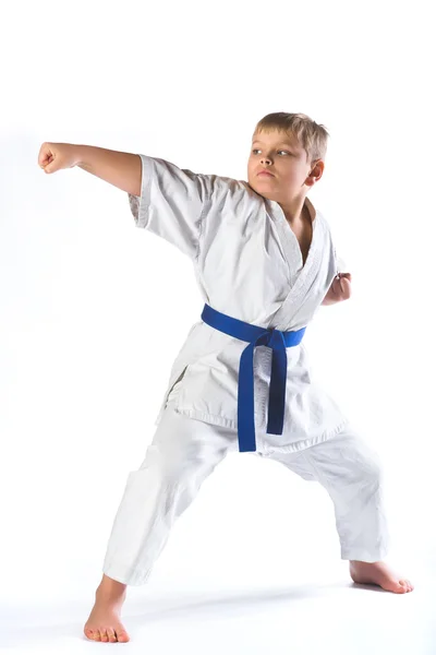 Pojke i kimono under utbildningen karate övningar på vit bakgrund — Stockfoto