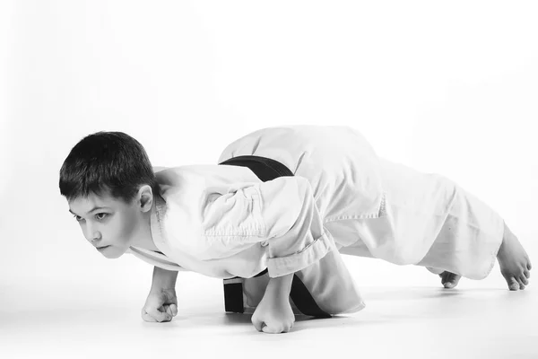 Niño en kimono durante el entrenamiento ejercicios de karate sobre fondo blanco — Foto de Stock