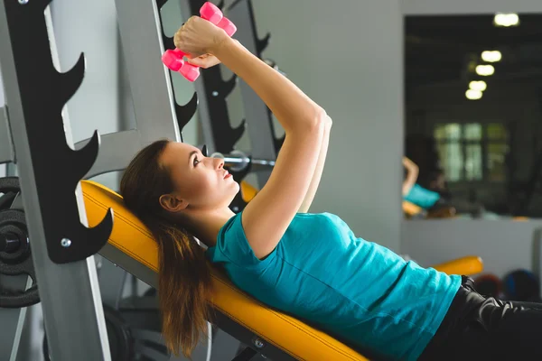 Mujer joven haciendo ejercicio con pesas en un gimnasio — Foto de Stock