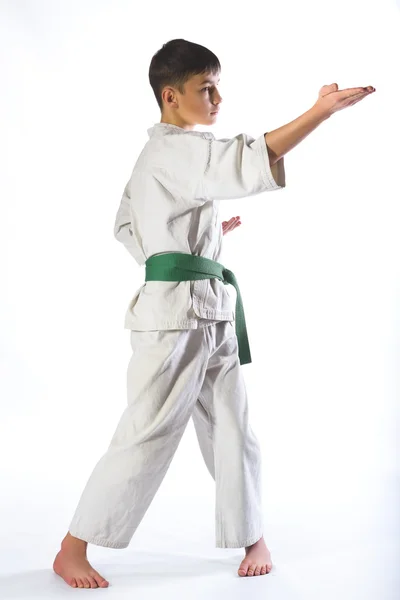 Ragazzo in kimono durante l'allenamento di karate esercizi su sfondo bianco — Foto Stock