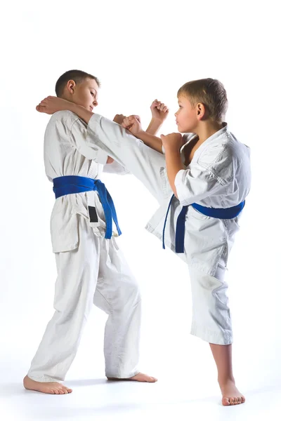 Karate ragazzo in kimono lotta su uno sfondo bianco — Foto Stock