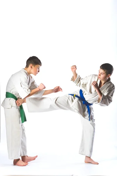 Jongens in kimono tijdens de training van karate oefeningen op witte achtergrond — Stockfoto