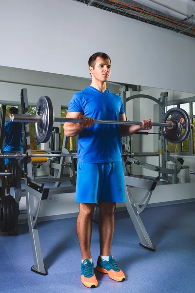 Atleta musculoso fisiculturista no ginásio treinamento com bar — Fotografia de Stock