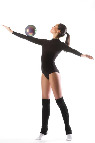 Giovane donna carina in tuta ginnasta mostrare abilità atletica con la palla ginnica su sfondo bianco — Foto Stock