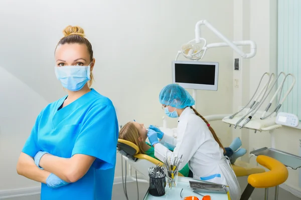 Οδοντίατρος σε χειρουργική μάσκα που στέκεται με τα χέρια διπλωμένα στο οδοντιατρείο — Φωτογραφία Αρχείου