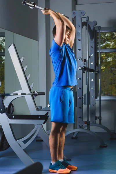 Exercício jovem atleta no ginásio - Ele está realizando exercícios tríceps — Fotografia de Stock