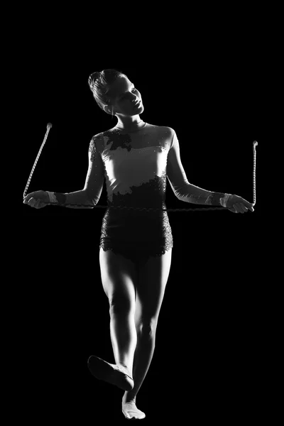Fitness, deporte, personas y concepto de salud - Mujer linda joven en traje de gimnasta muestran habilidad atlética en el fondo negro —  Fotos de Stock