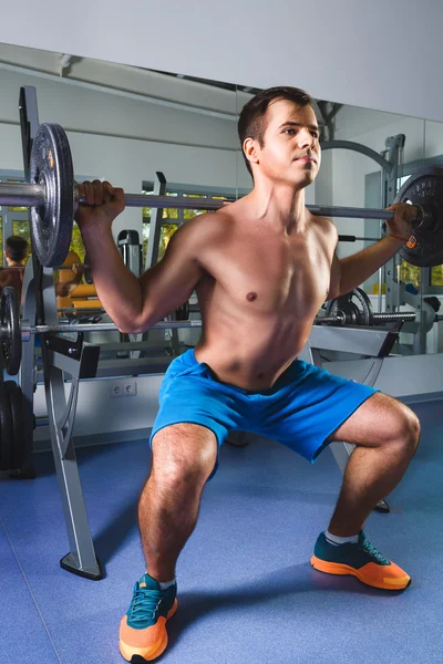 Sport, musculation, style de vie et concept de personnes - jeune homme avec haltère faire squats dans la salle de gym — Photo
