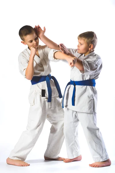 Niños en kimono durante el entrenamiento ejercicios de karate sobre fondo blanco — Foto de Stock