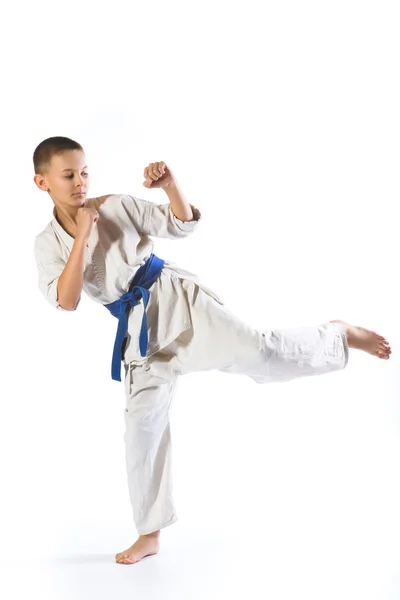 Niño en kimono durante el entrenamiento ejercicios de karate sobre fondo blanco — Foto de Stock