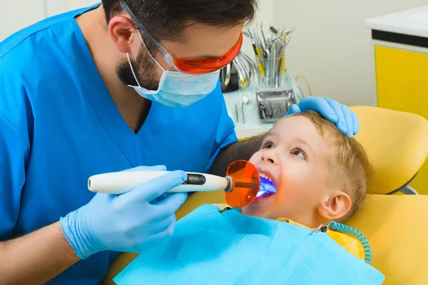 Dentista trata dentes de paciente em clínica odontológica — Fotografia de Stock