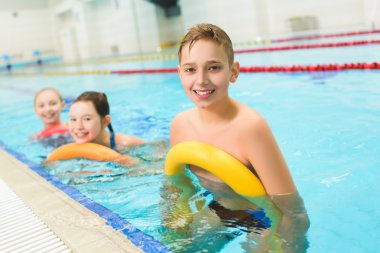 Mutlu ve gülümseyerek grup çocuk havuzu noodle ile yüzmek için öğrenme