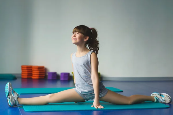 Chica sentada y hace estiramientos o ejercicios de gimnasia en la clase para la aptitud —  Fotos de Stock