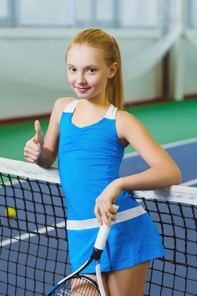 Симпатичная девушка играет в теннис и позирует или показывает большой палец в зале суда — стоковое фото